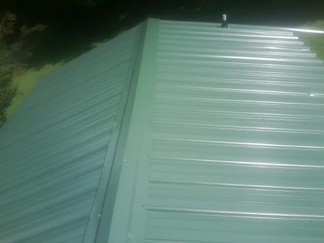 New green metal panels meeting at the ridge of a roof — Flat Roof Repair work by our crew in Anaheim