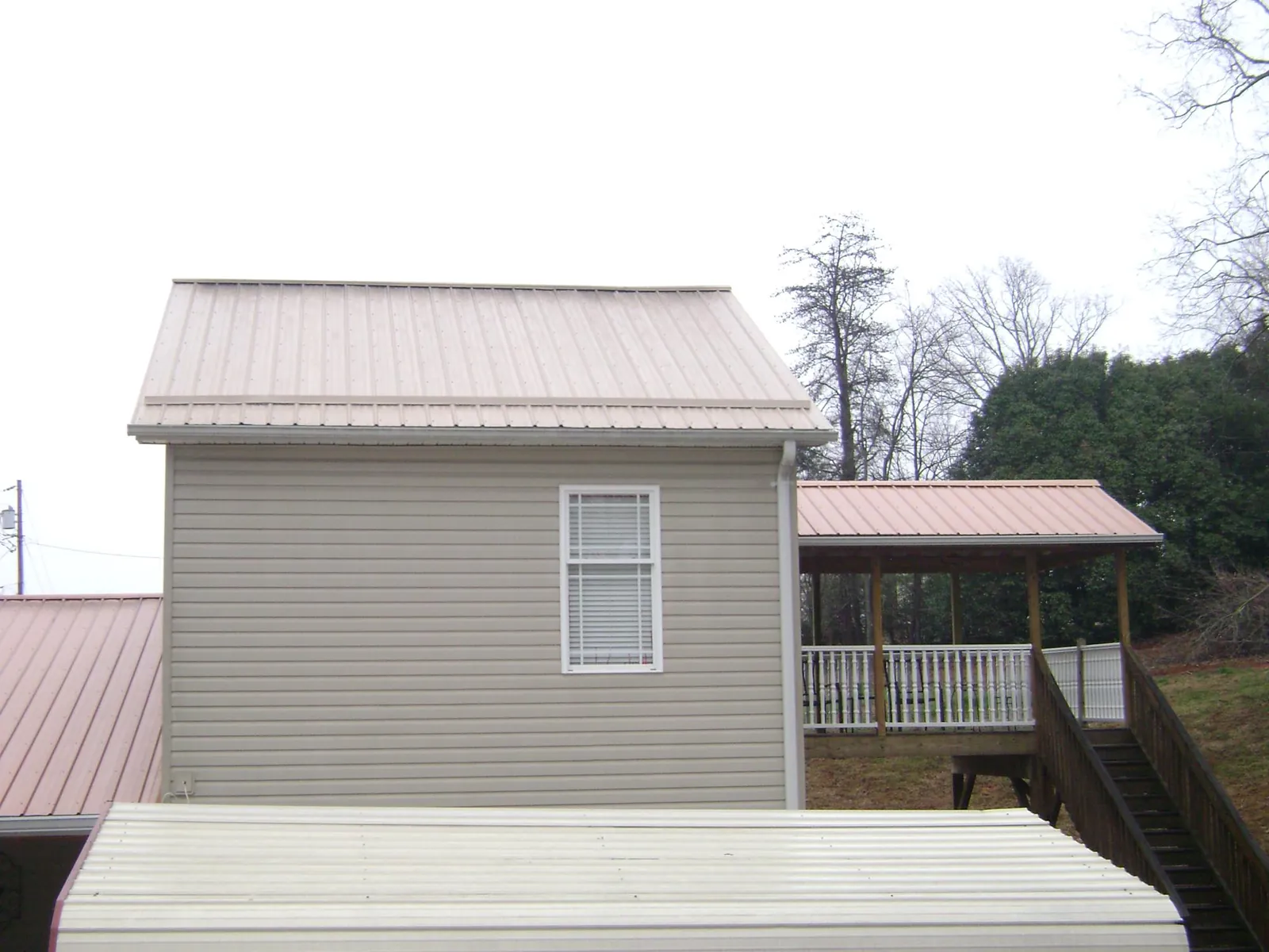 Tan metal roofs on a two story addition and attached porch, from a Roof Replacement job in Anaheim