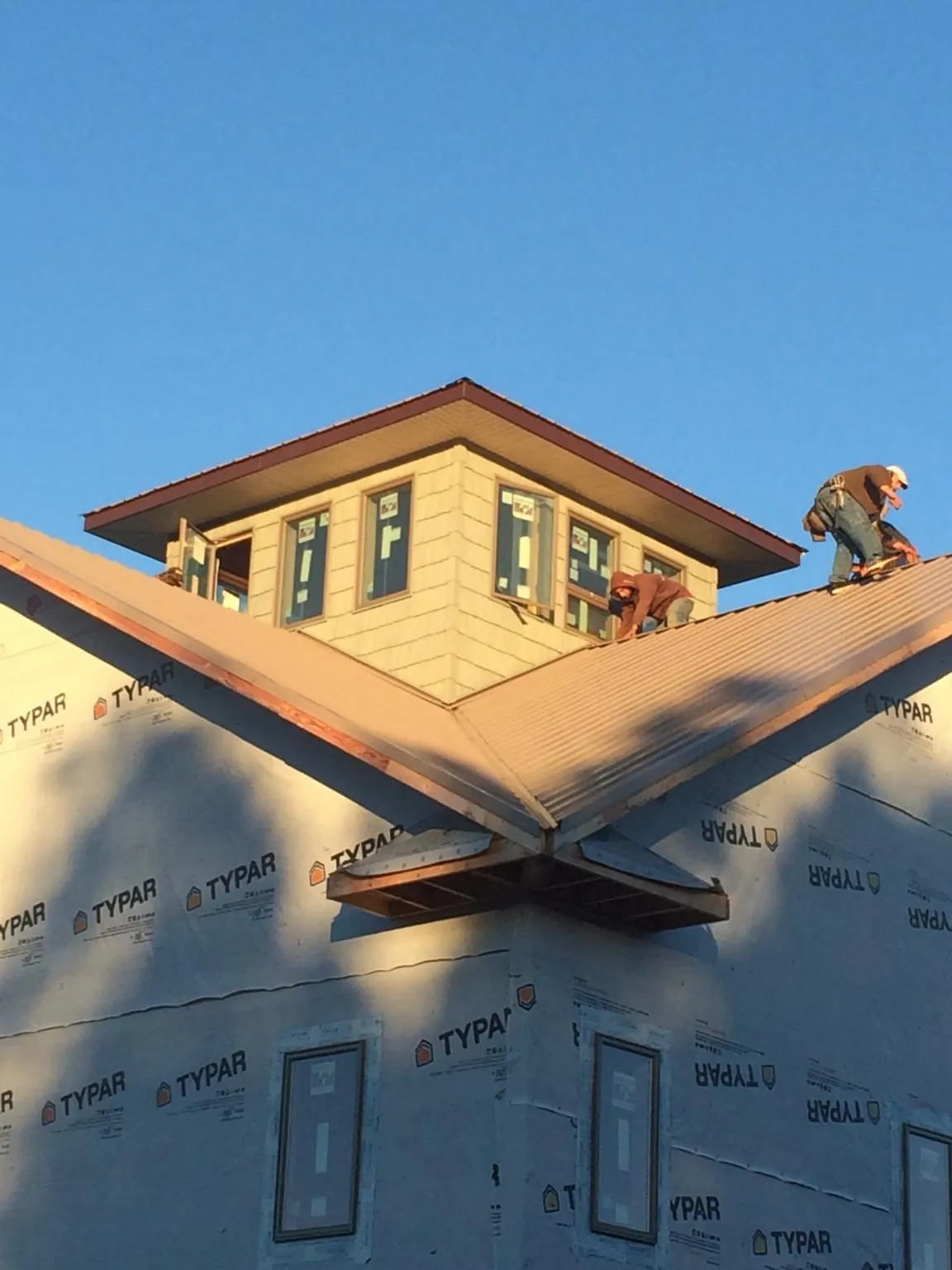Roofers working around a rooftop cupola on a new metal roof at sunset — Roof Waterproofing in Anaheim by Roofing Brothers
